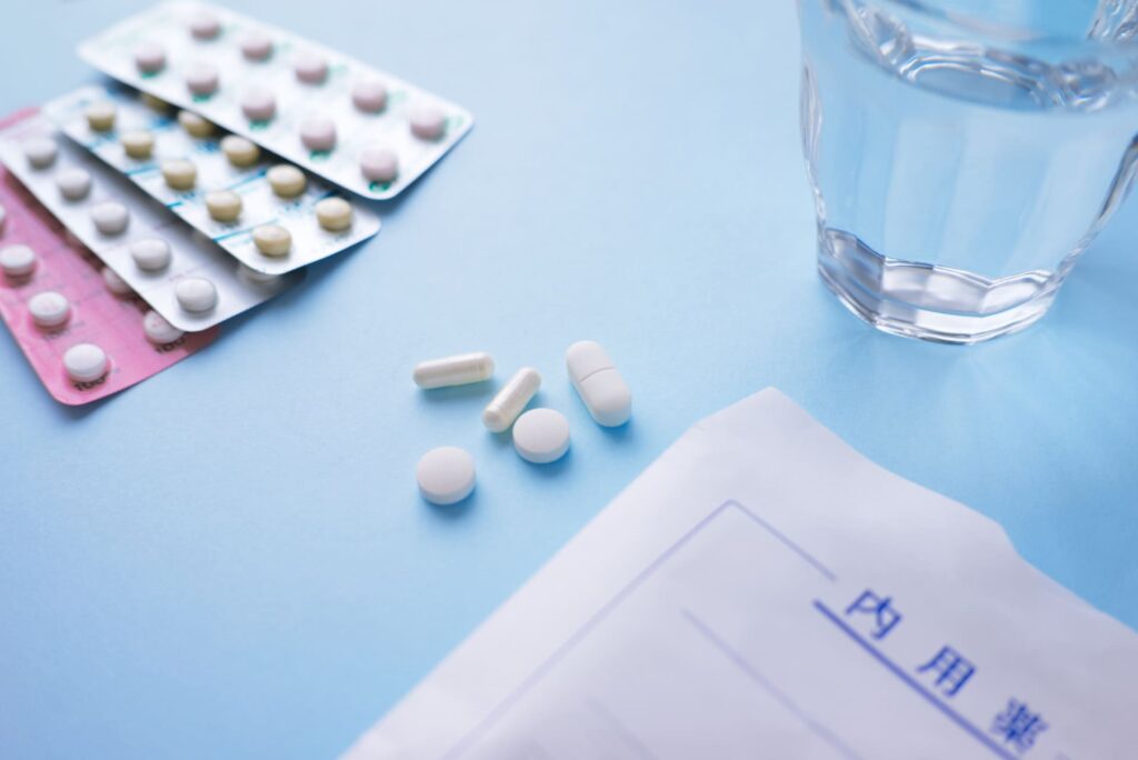 コップの水と一緒に置かれた薬のイメージ写真