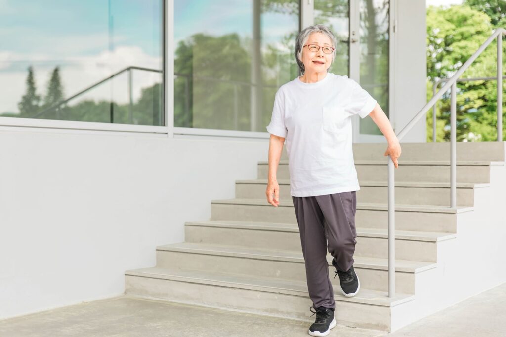 手すりを持って階段を下りる高齢女性