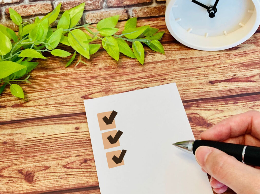 チェックリストにペンでチェックを入れている手元の写真