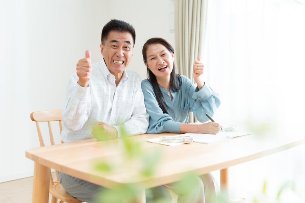 自宅で笑顔で並ぶ中年夫婦の生活イメージ