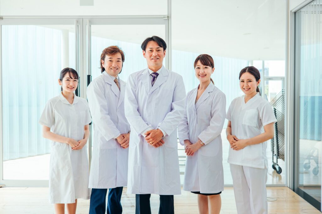 歯科医院で白衣を着て並んでいる男女5人のスタッフの様子