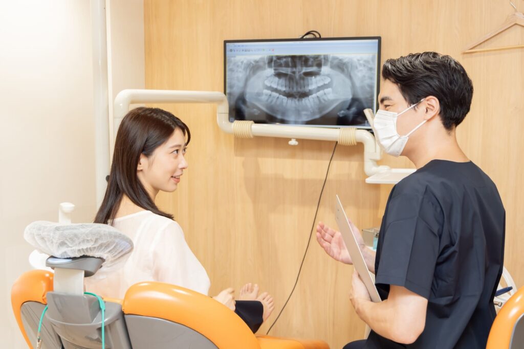 歯科医院の診療室で歯科医師と患者が治療について話している様子