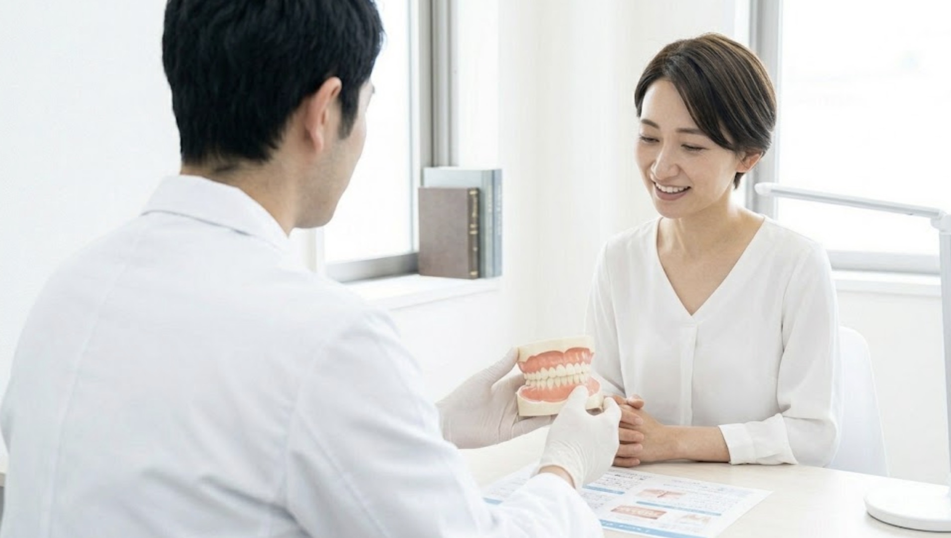 カウンセリング室で歯の模型の説明を受け、安心する女性の様子