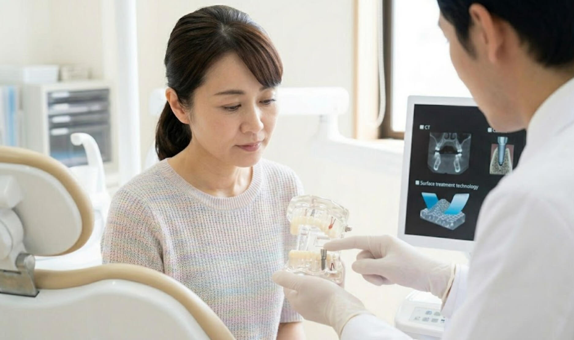 精密なインプラントシステムの利点について、模型を指差して説明するシーン