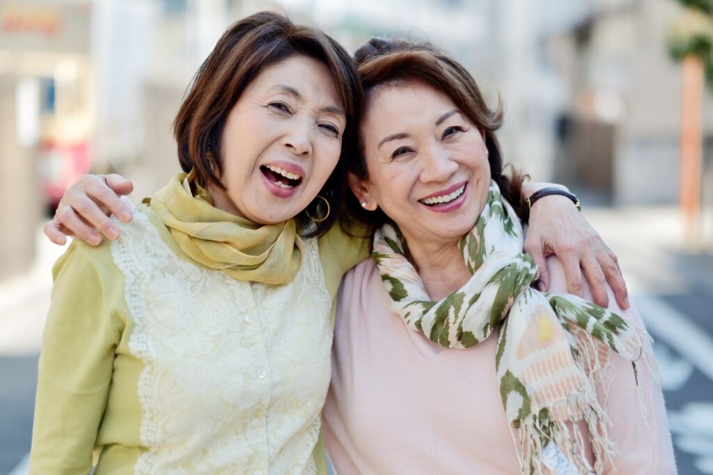 女性二人が笑顔で肩を組んでいる写真