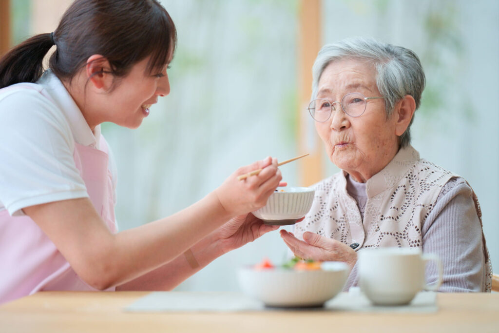 高齢女性の食事介助をする女性の様子