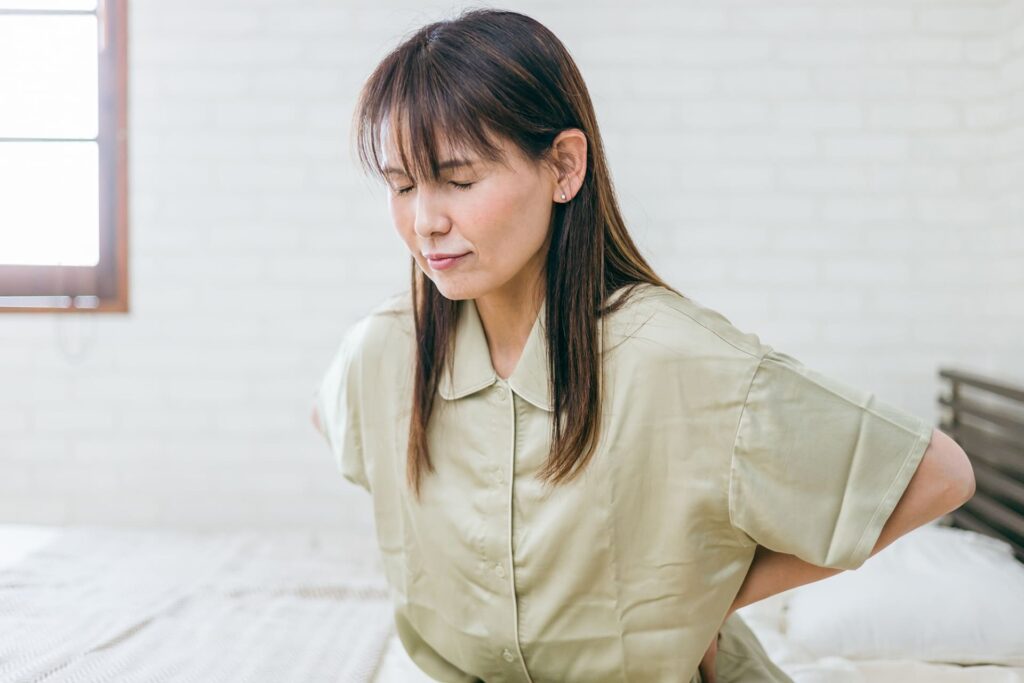 腰に手を当てて不調を感じている女性