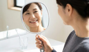 鏡を見て自信を持って微笑む、健康な口元の日本人女性の様子
