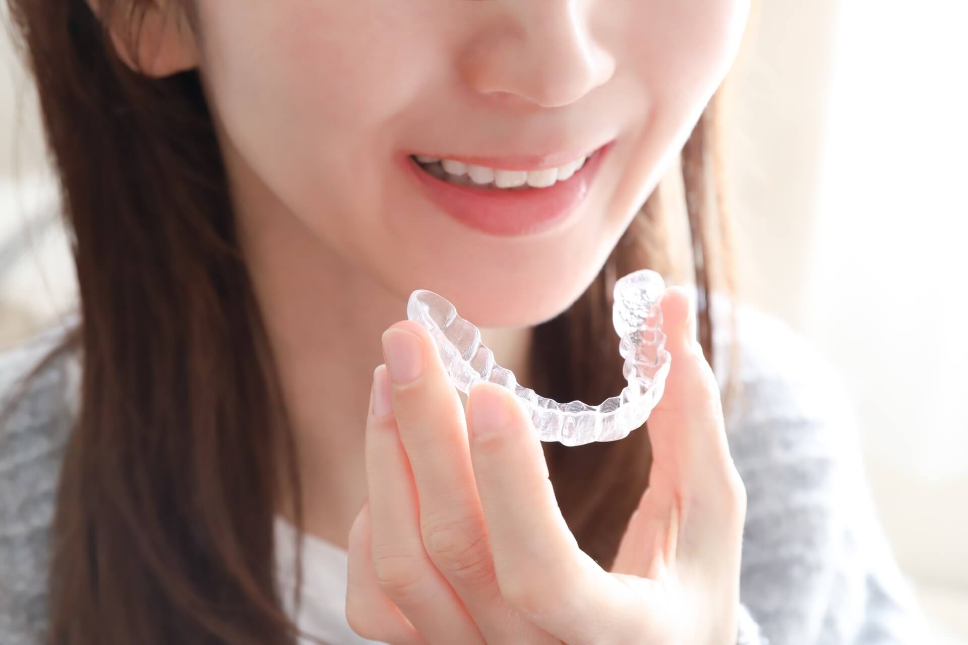 矯正用マウスピースを持つ女性の口元