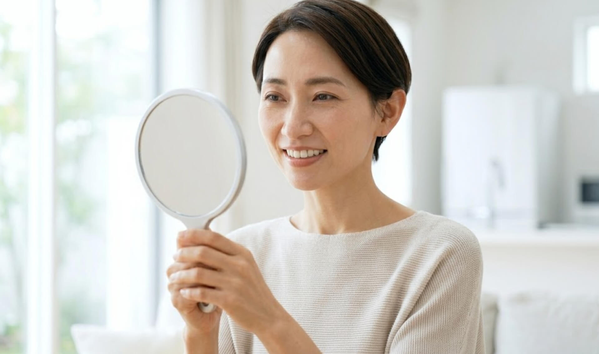 手鏡を覗き込み、自然な笑顔で自信を持つ日本人女性の様子