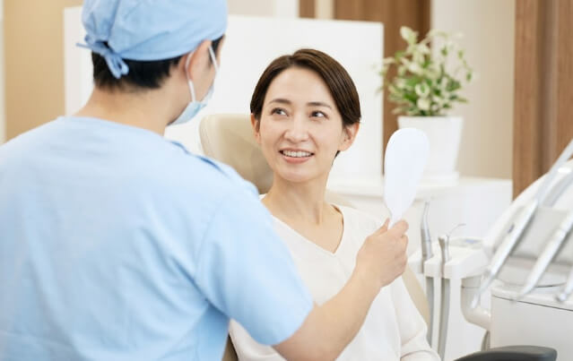 歯科検診中に、顔の見えない歯科医師と和やかに会話する日本人女性