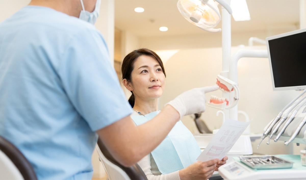 歯科医院で歯科医師から治療の説明を受けている女性の様子