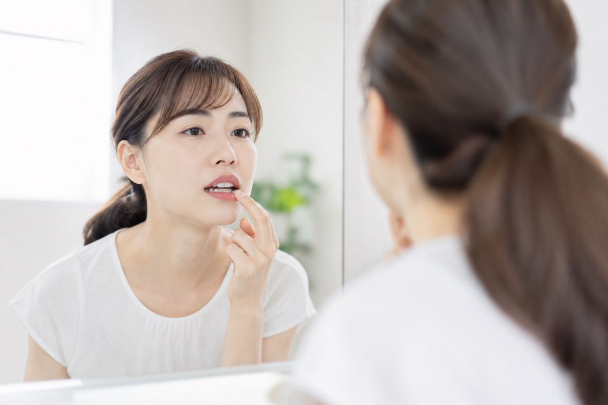洗面所の鏡で歯ぐきの状態を確かめる女性の様子